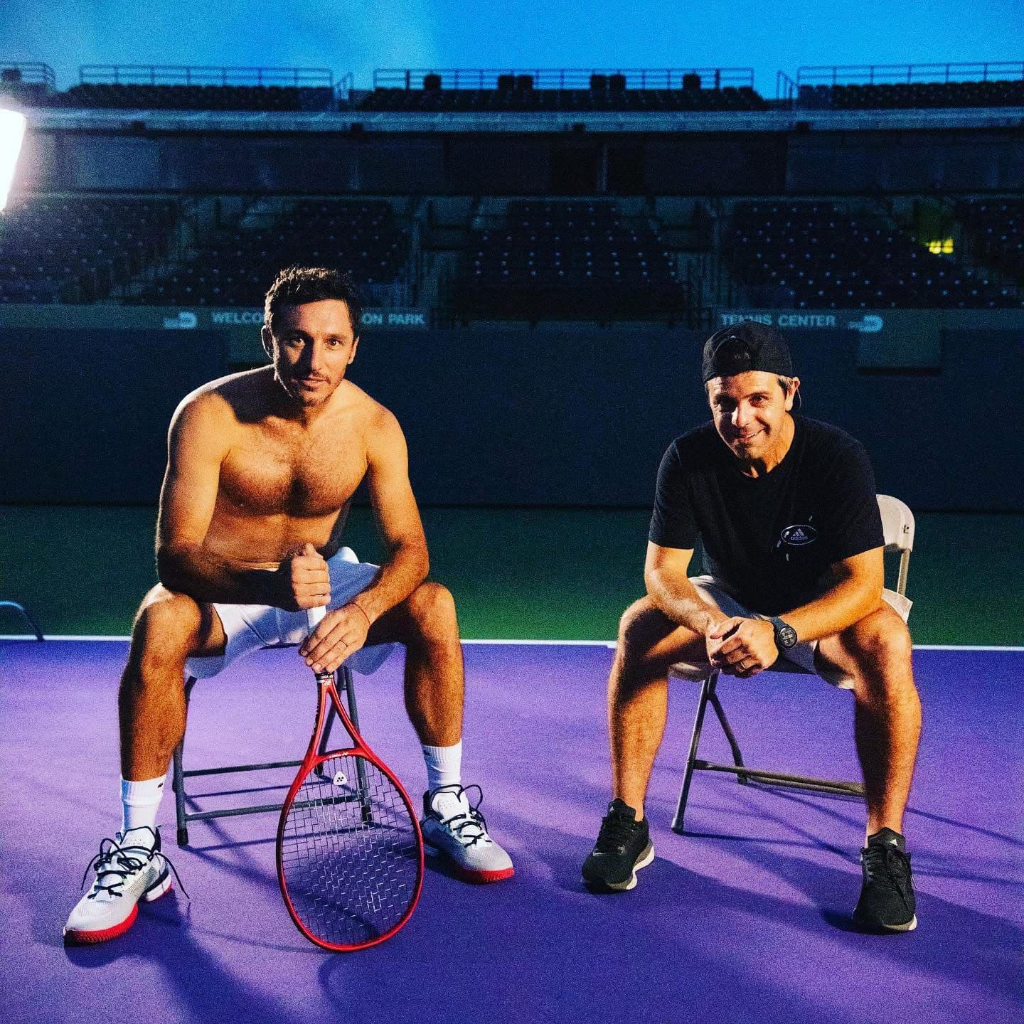 Juan Pablo Pagano sentado junto a un tenista en una cancha iluminada de noche